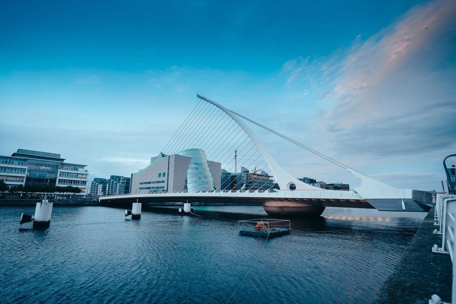 The iconic Samuel Beckett Bridge in Dublin spans the river against a vibrant blue sky.